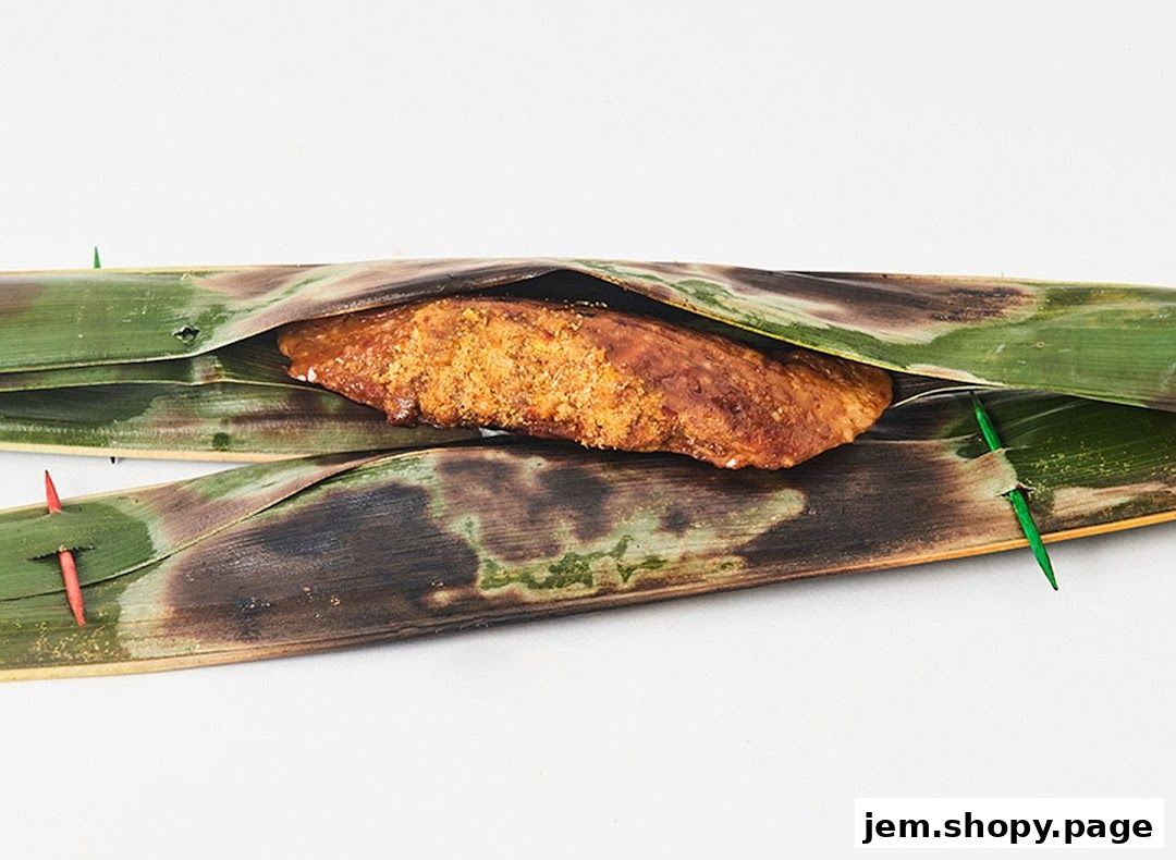 A close-up of a grilled food item wrapped in banana leaves, secured with toothpicks.