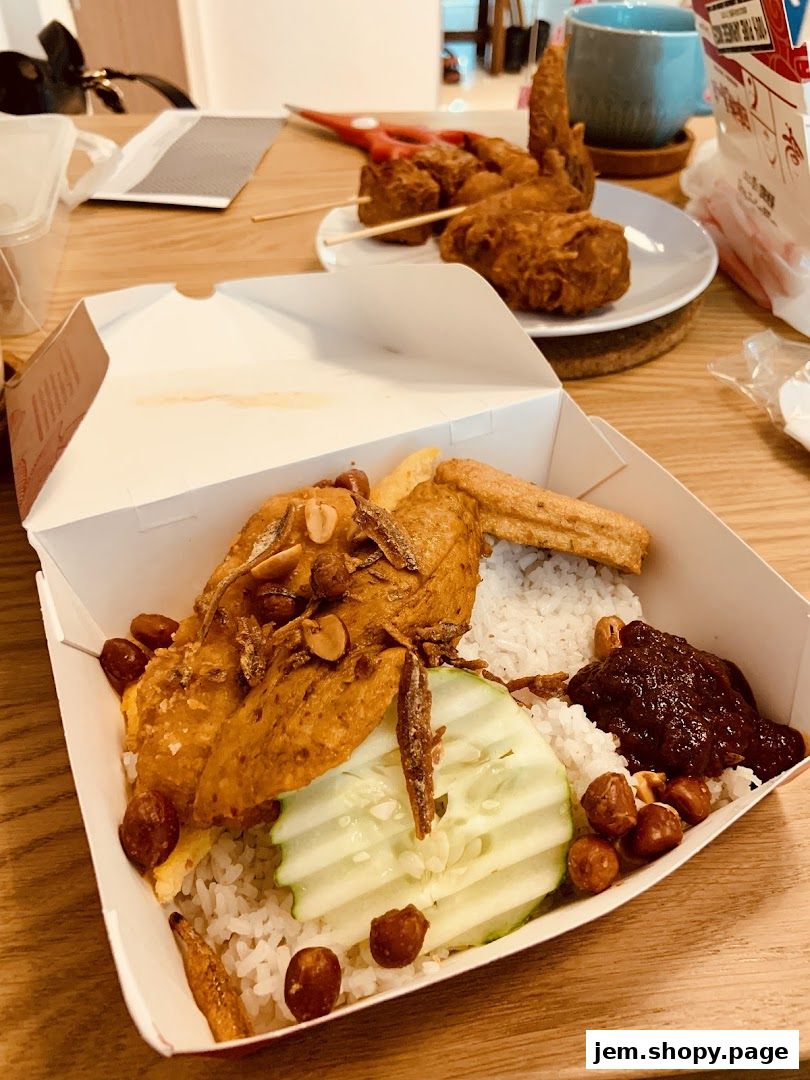 A close-up of a takeaway box filled with Nasi Lemak and fried chicken.
