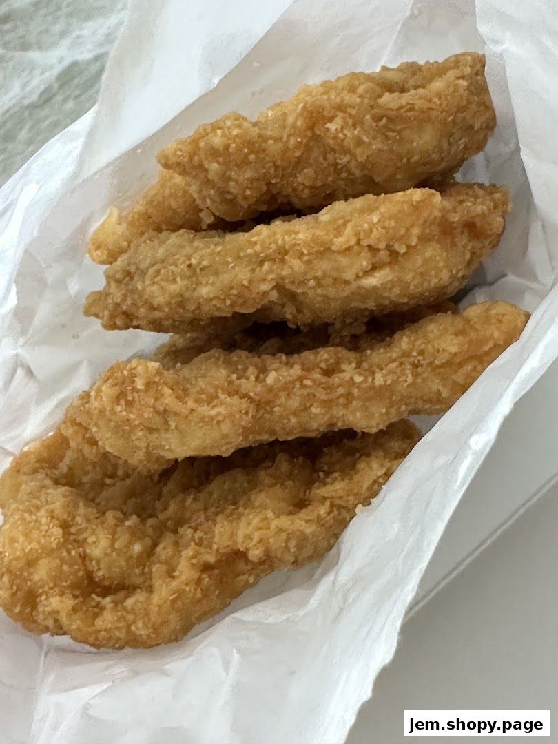 Crispy golden fried chicken tenders served in white paper packaging.