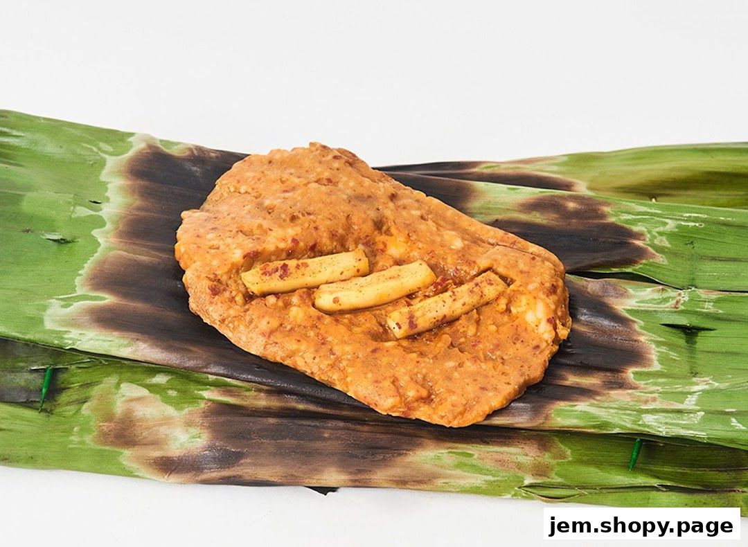 A close-up of a grilled dish wrapped in banana leaves, topped with small pieces of food.
