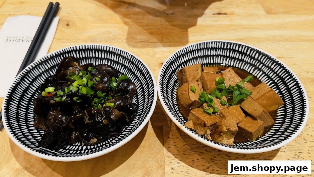 Two bowls of appetizers, one with wood ear mushrooms and the other with braised tofu, are served.
