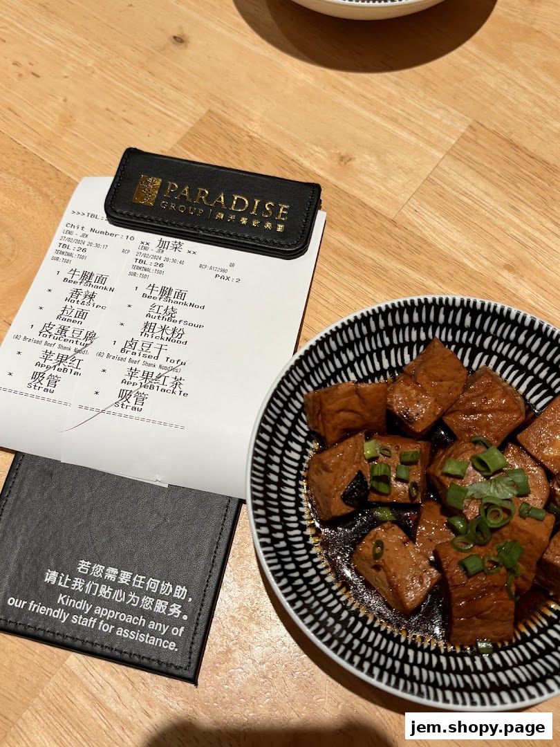 A plate of braised tofu and a receipt from LeNu Chefs Wai Noodle Bar.