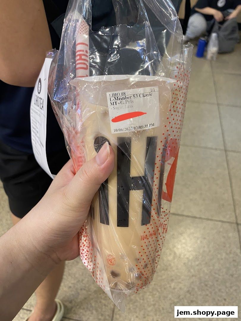 A hand holds a plastic bag with a LiHO TEA drink and a receipt.