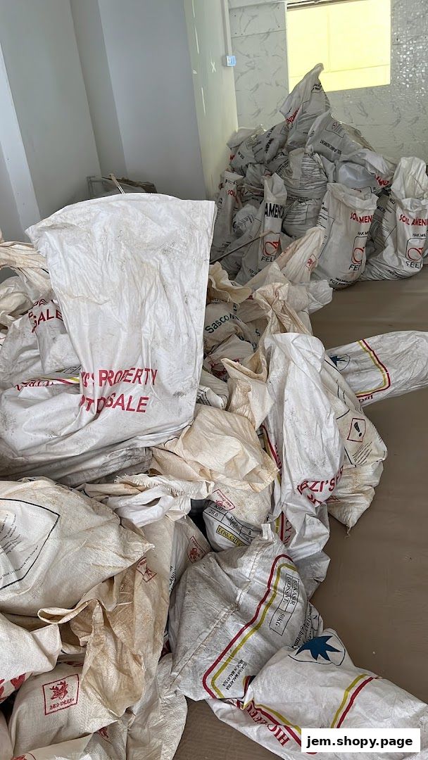 A pile of large white sacks, some with red text indicating property for sale.