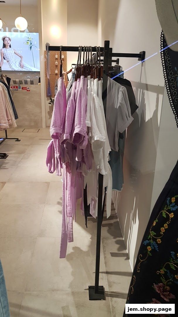 Clothing displayed on racks inside a boutique store, featuring pastel colors and stylish designs.