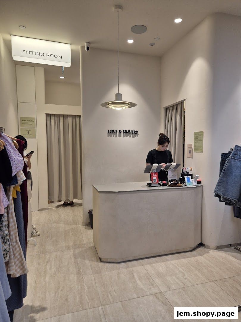 Interior of a clothing store with a fitting room, counter, and clothing racks.