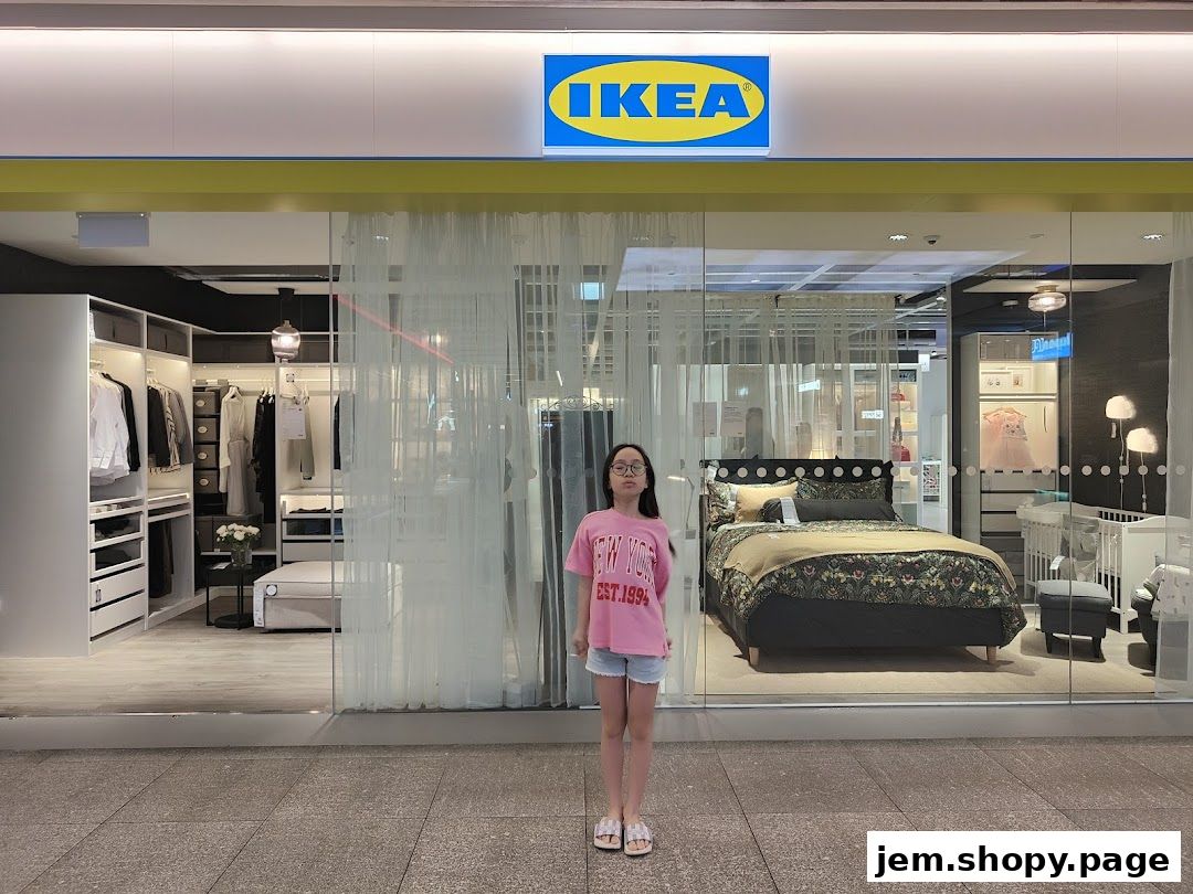 A young girl stands in front of the IKEA store entrance showcasing bedroom and closet displays.