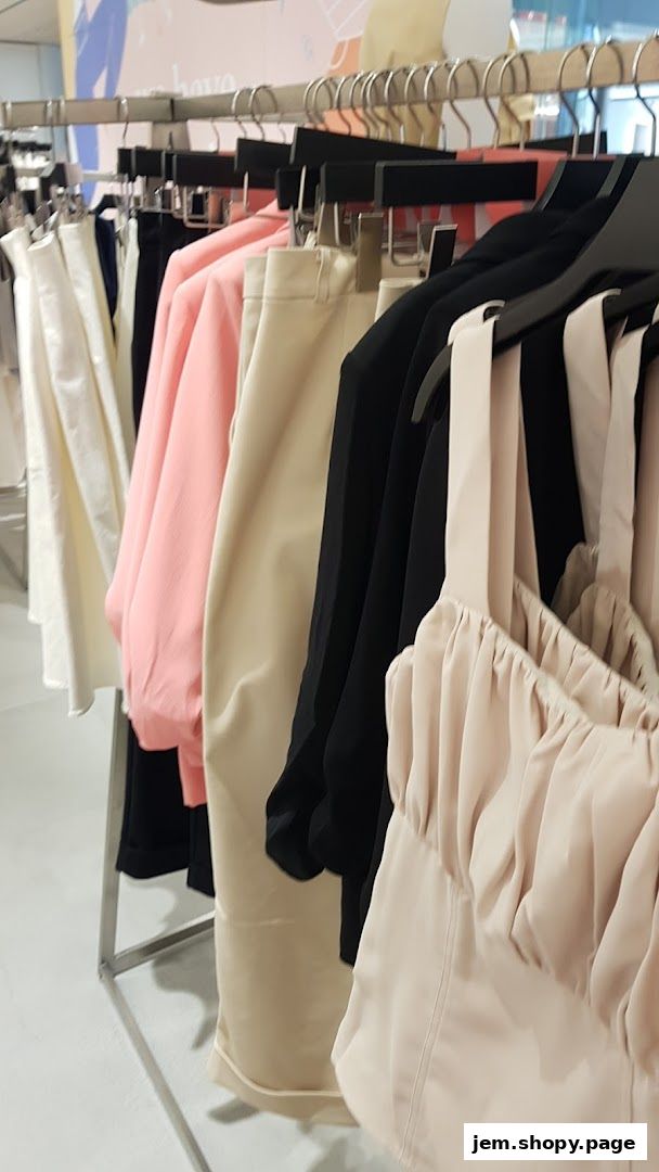 A rack of women's clothing in various colors, including white, pink, beige, and black.