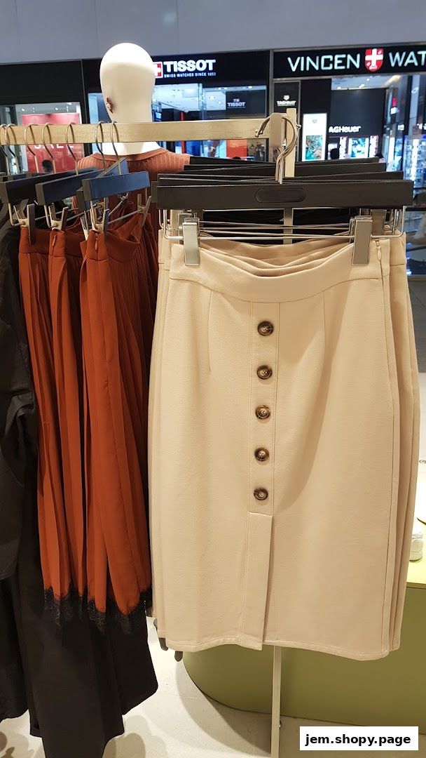 A mannequin displays a beige skirt with buttons, next to rust-colored pleated skirts.