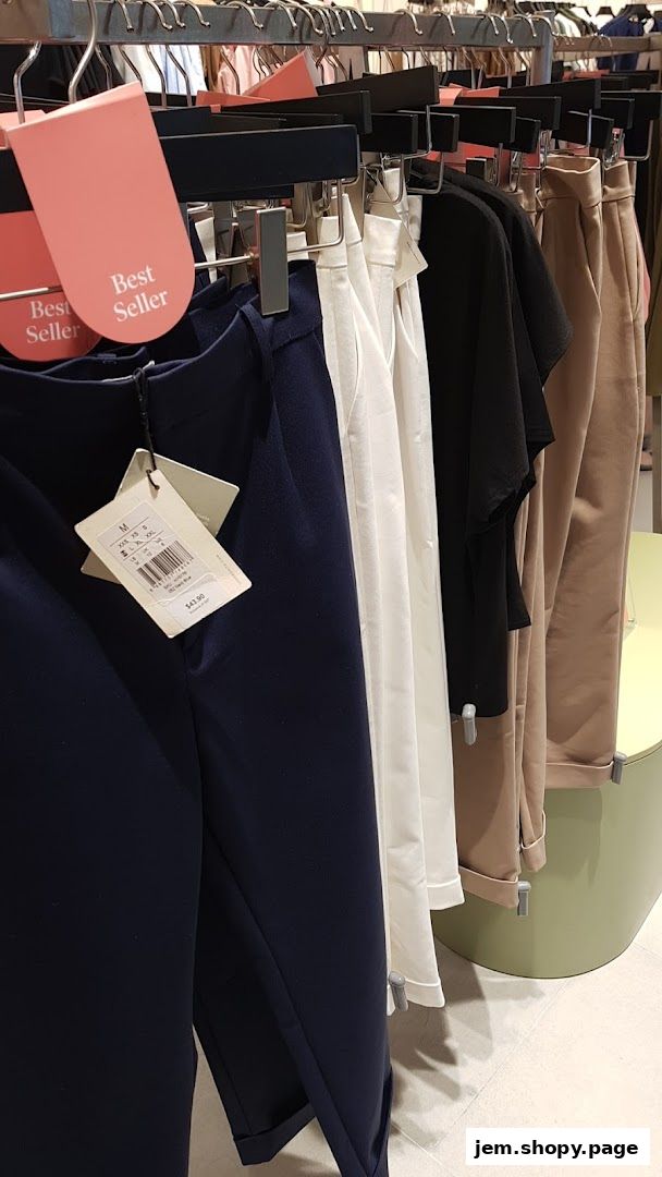Close-up of women's clothing racks featuring navy, white, black, and beige pants.