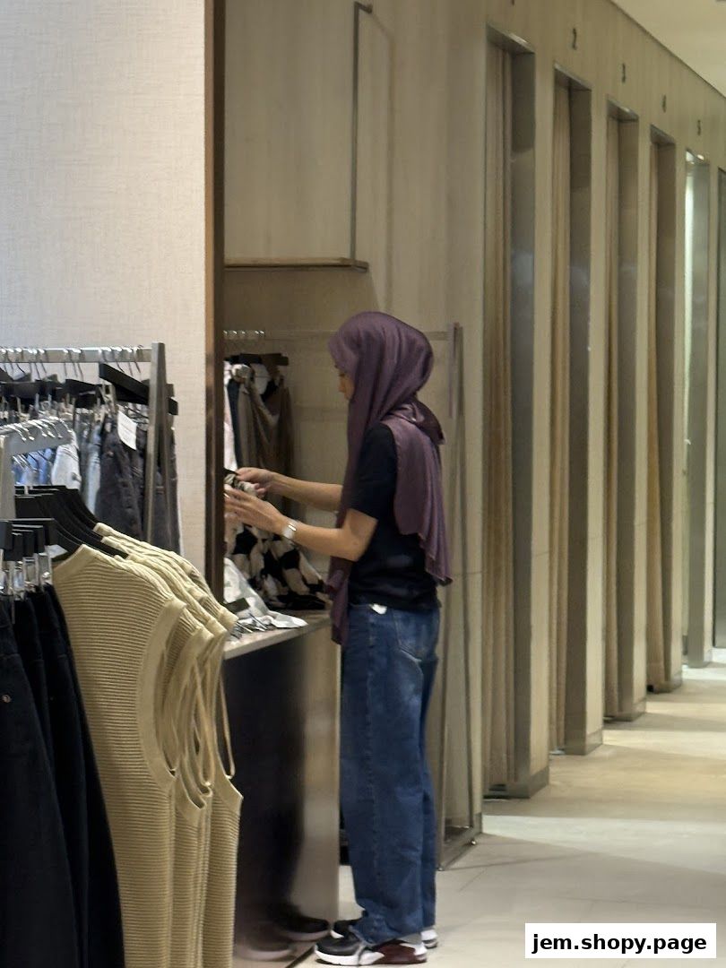 A woman browses clothing racks inside a modern fashion boutique.