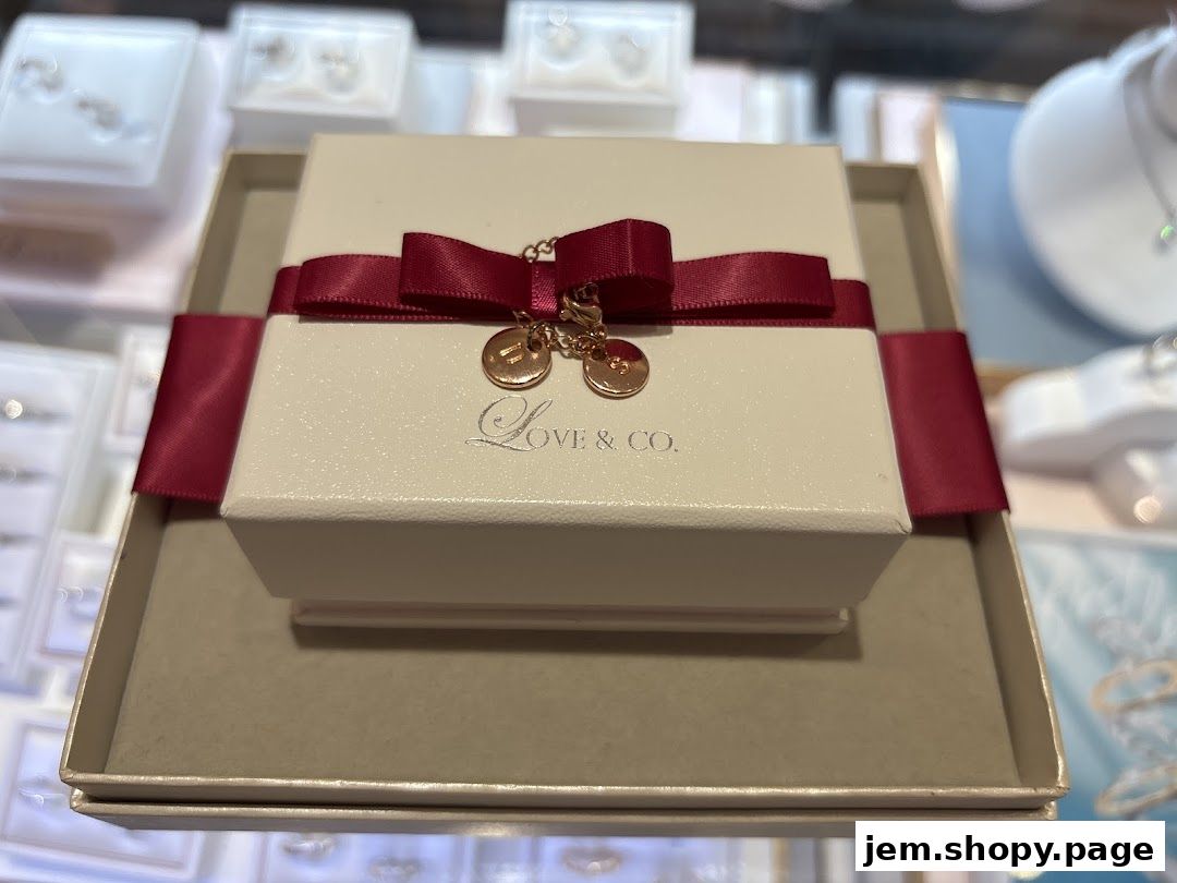 A jewelry box from Love & Co. with a red ribbon and charms.