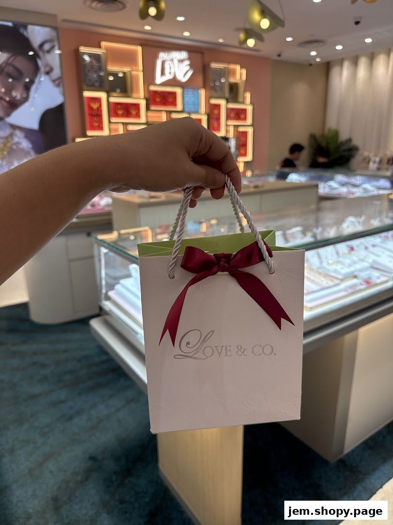 A hand holds a Love & Co. shopping bag inside a jewelry store.