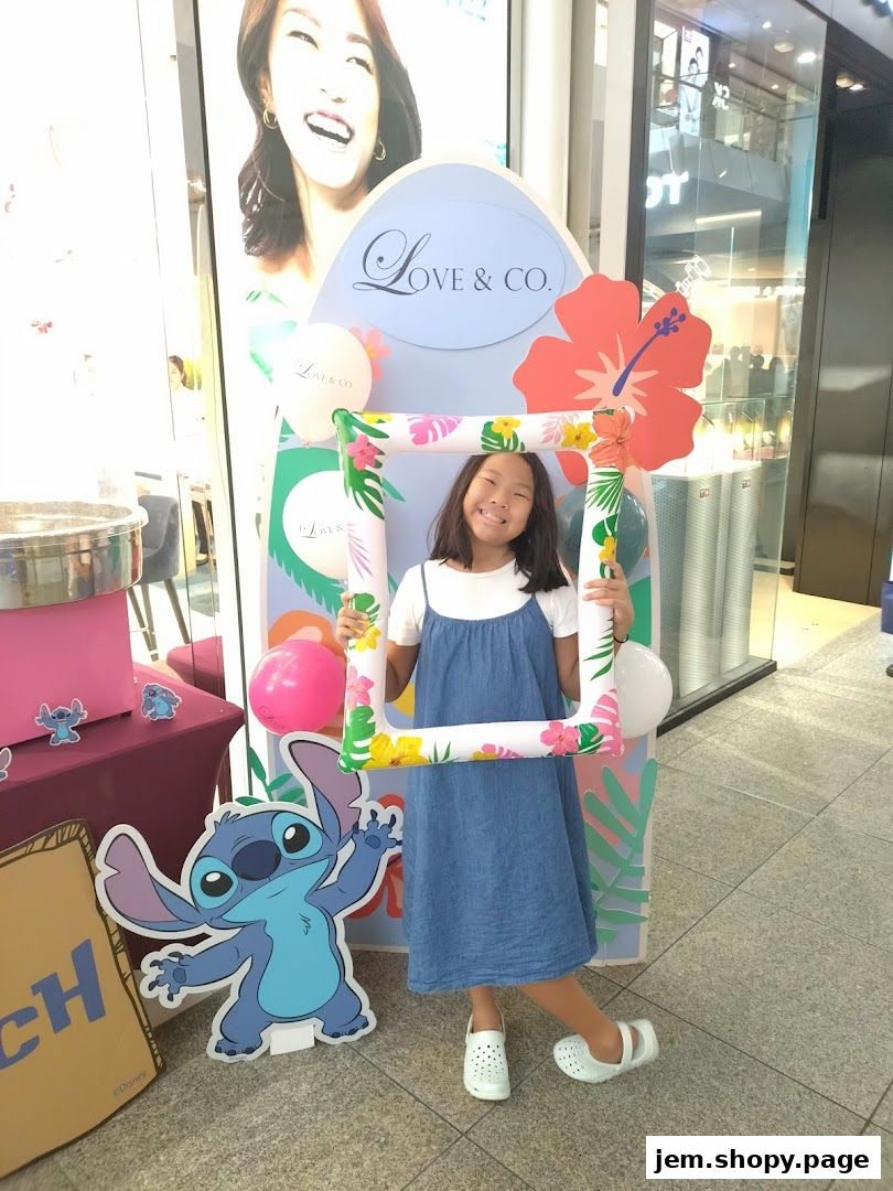 A young girl poses with a photo frame at a Love & Co. promotional display featuring Stitch.