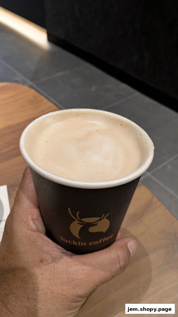 A hand holds a cup of coffee with the Luckin Coffee logo.