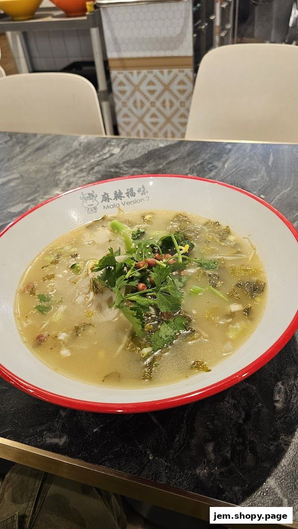 A close-up of a steaming bowl of noodle soup with fresh herbs and peanuts.