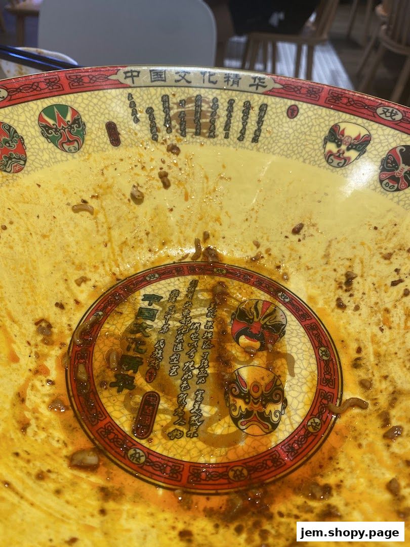 A close-up of a decorative bowl with Chinese cultural motifs and remnants of food.