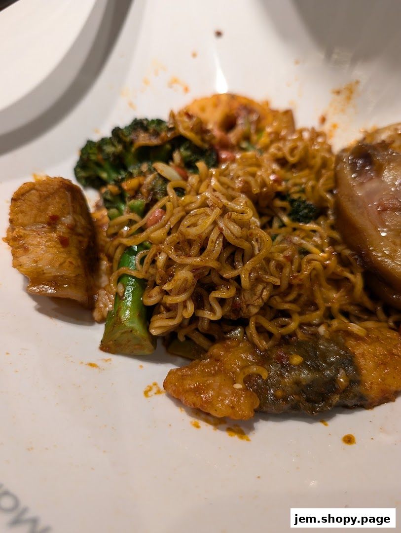A close-up of a spicy noodle dish with broccoli and meat on a white plate.