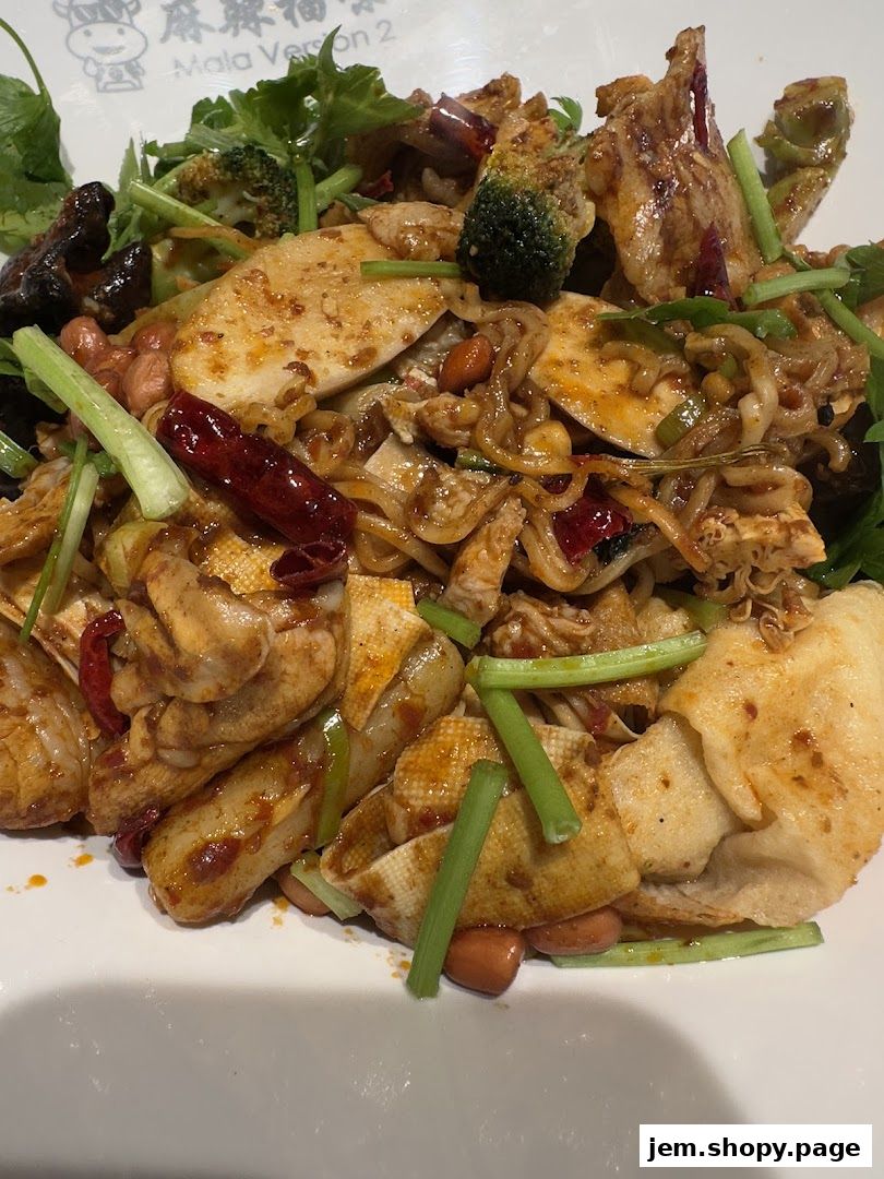 A close-up of a spicy mala dish with tofu, broccoli, peanuts, and chili peppers.