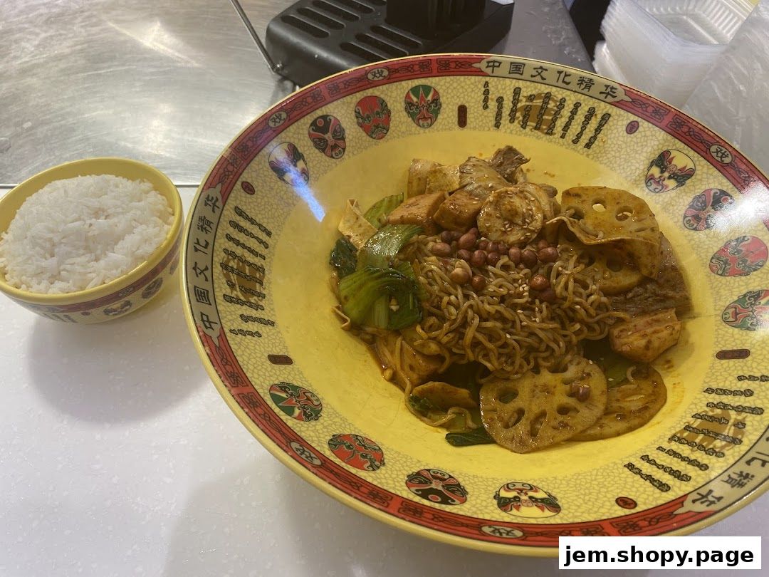 A bowl of rice next to a large yellow bowl filled with noodles, lotus root, and vegetables.
