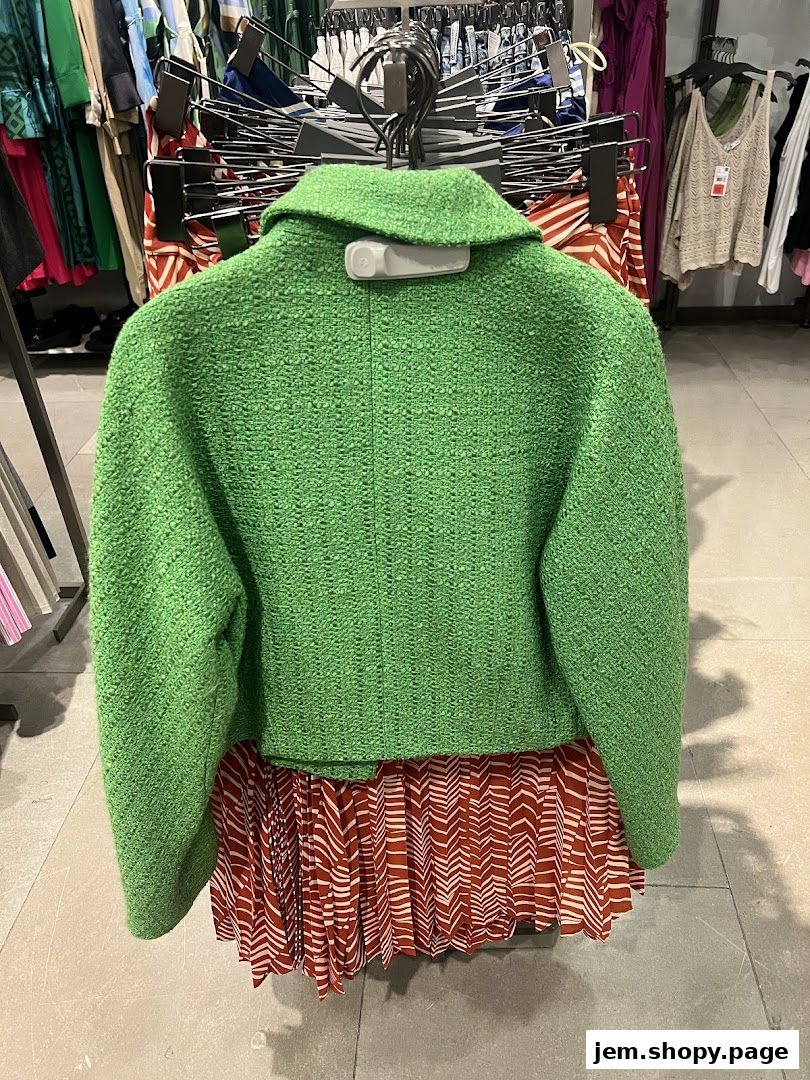 A bright green textured jacket displayed on a hanger in a clothing store.