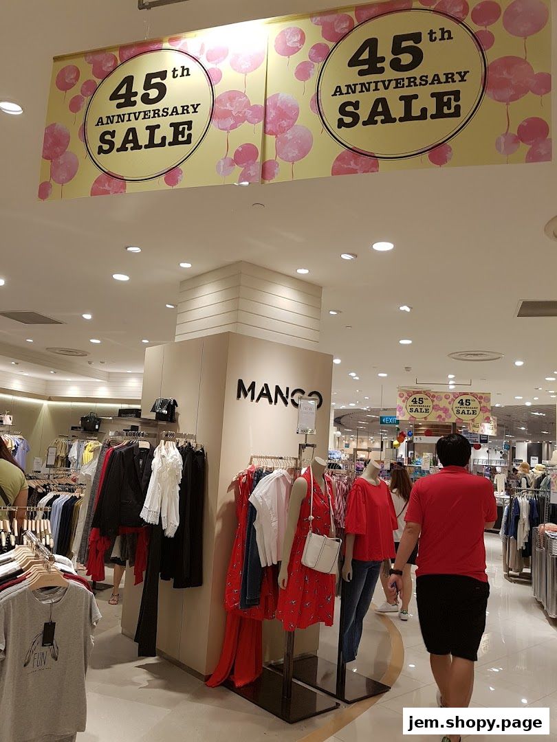 MANGO store interior with mannequins displaying red outfits and anniversary sale banners.