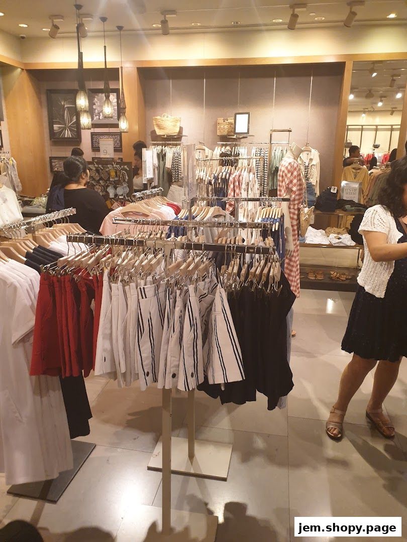 Interior view of a MANGO clothing store with racks of apparel and shoppers.