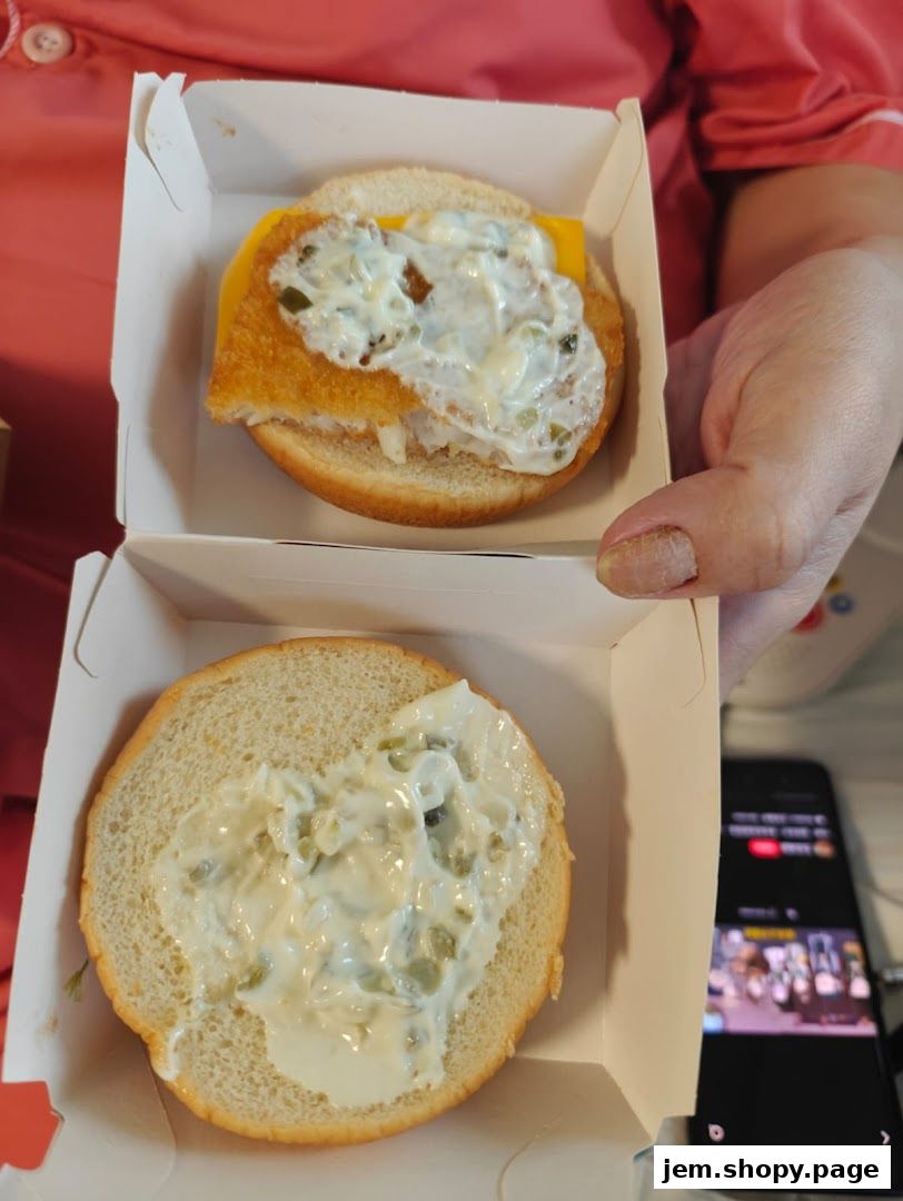 A person holding two halves of a fish sandwich from McDonald's.