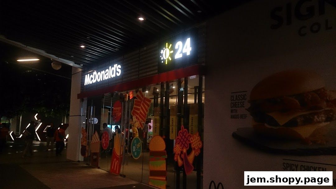 Exterior of a McDonald's restaurant at night, featuring its signage and a large burger advertisement.