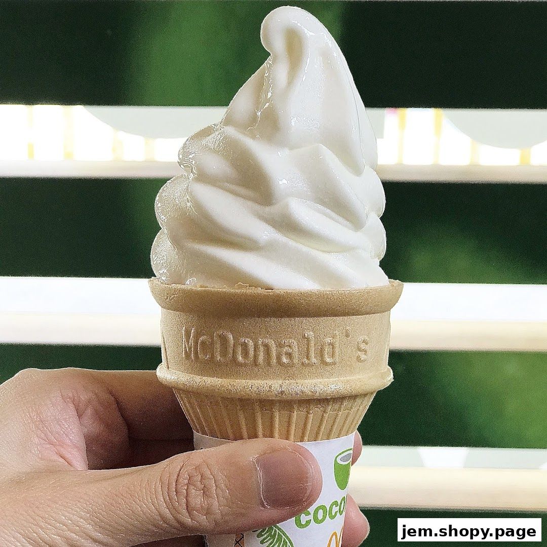 A hand holds a McDonald's soft-serve ice cream cone with a green background.