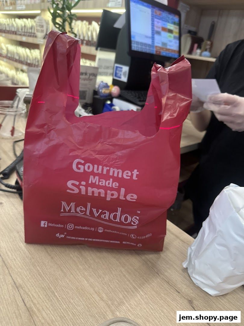 A red Melvados shopping bag with 'Gourmet Made Simple' text sits on a wooden counter.