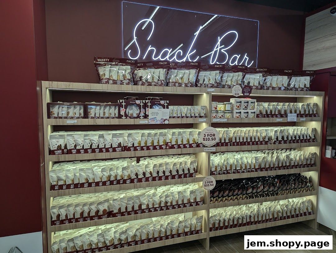 A well-stocked snack bar with shelves full of packaged snacks and a neon 'Snack Bar' sign.