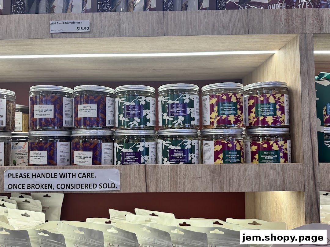 Jars of cookies and snacks displayed on shelves with a 'handle with care' sign.