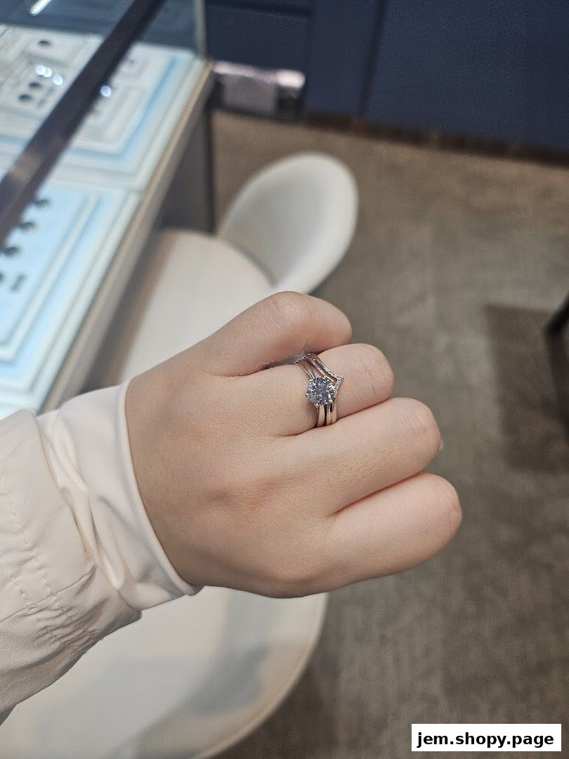 A hand wearing a diamond engagement ring and wedding band in a jewelry store.