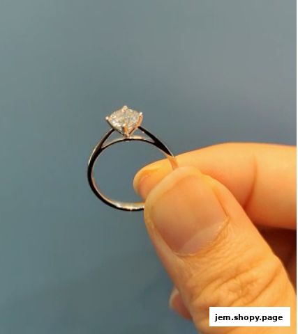 A hand holds a diamond engagement ring with a square-cut stone.