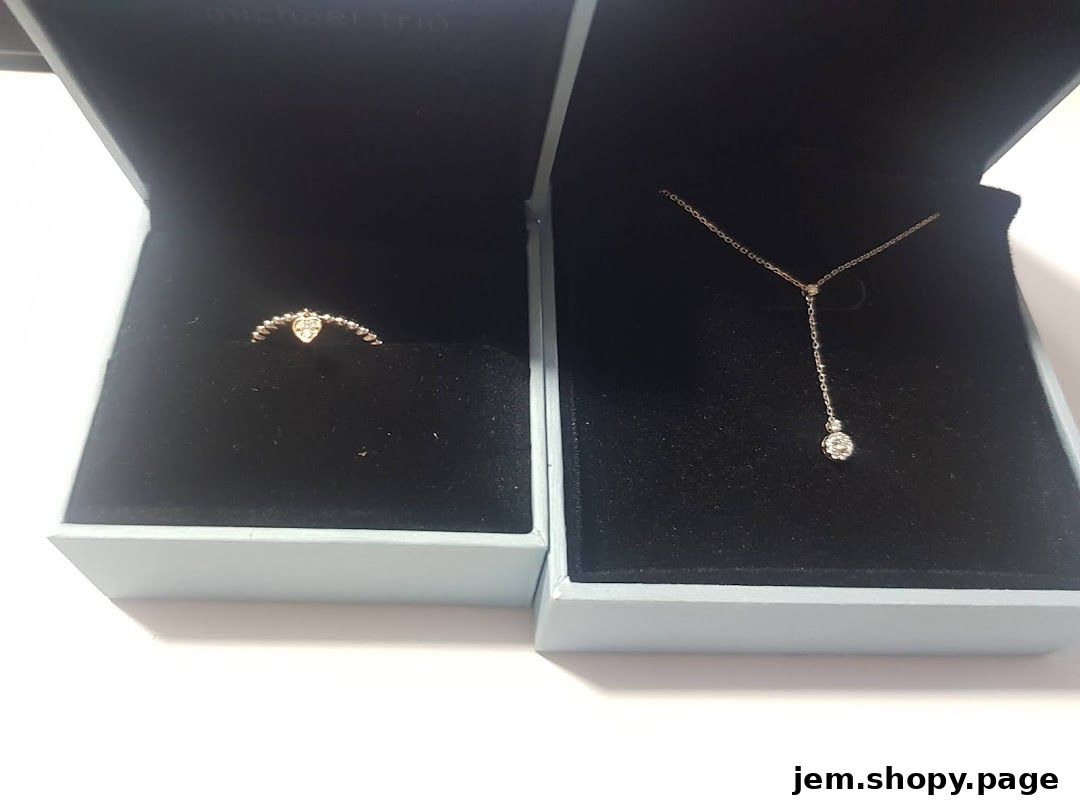 A diamond ring and necklace displayed in their respective gift boxes.