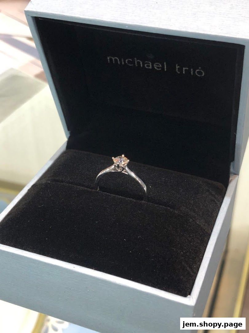 A diamond ring is displayed in an open Michael Trio jewelry box.