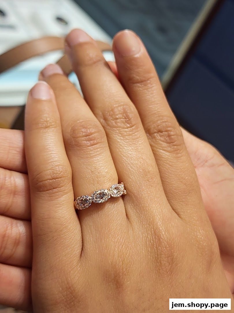 A close-up shot of a hand wearing a delicate rose gold ring with sparkling stones.