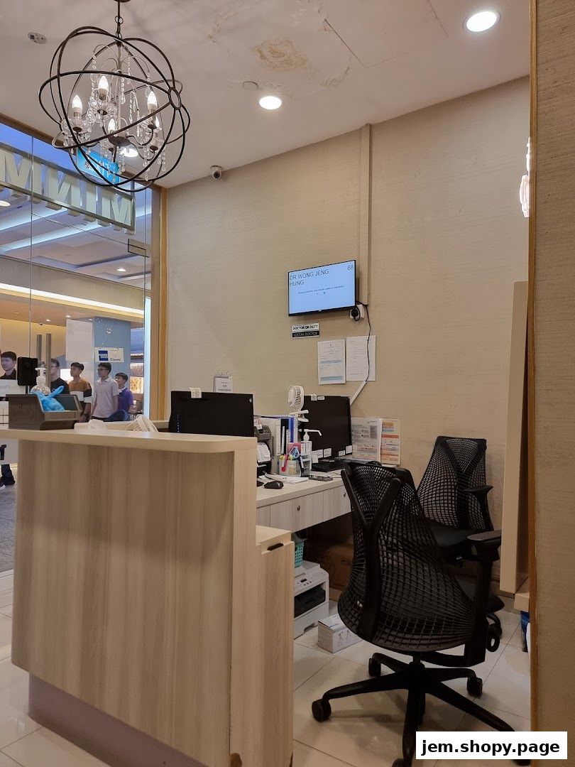 Reception area of Minmed Clinic Jurong East with a desk, chairs, and a screen displaying doctor information.