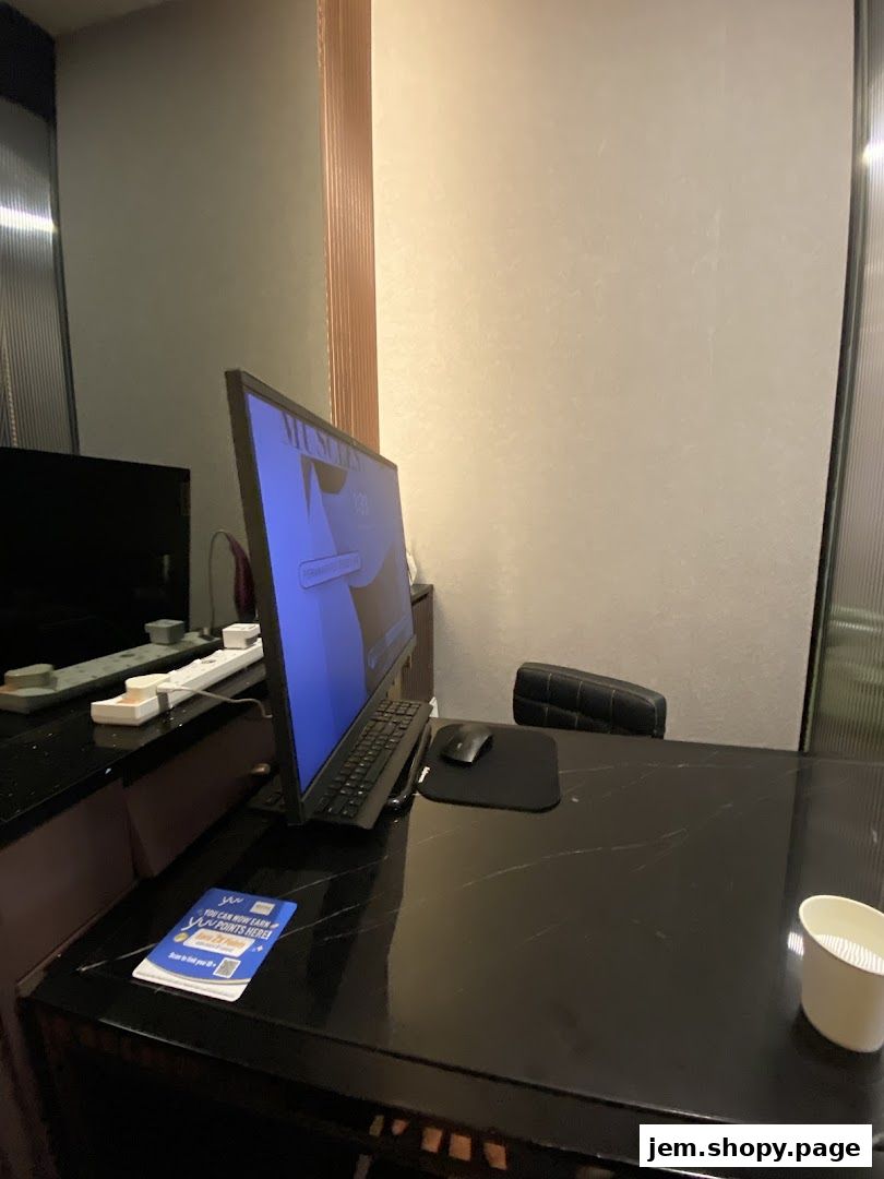 A desk with a computer monitor, keyboard, mouse, and a promotional flyer.