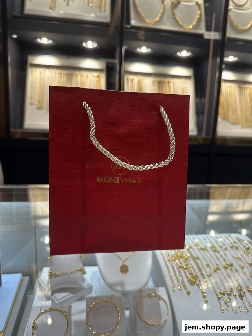 A red MoneyMax shopping bag is displayed in front of a jewelry display case.