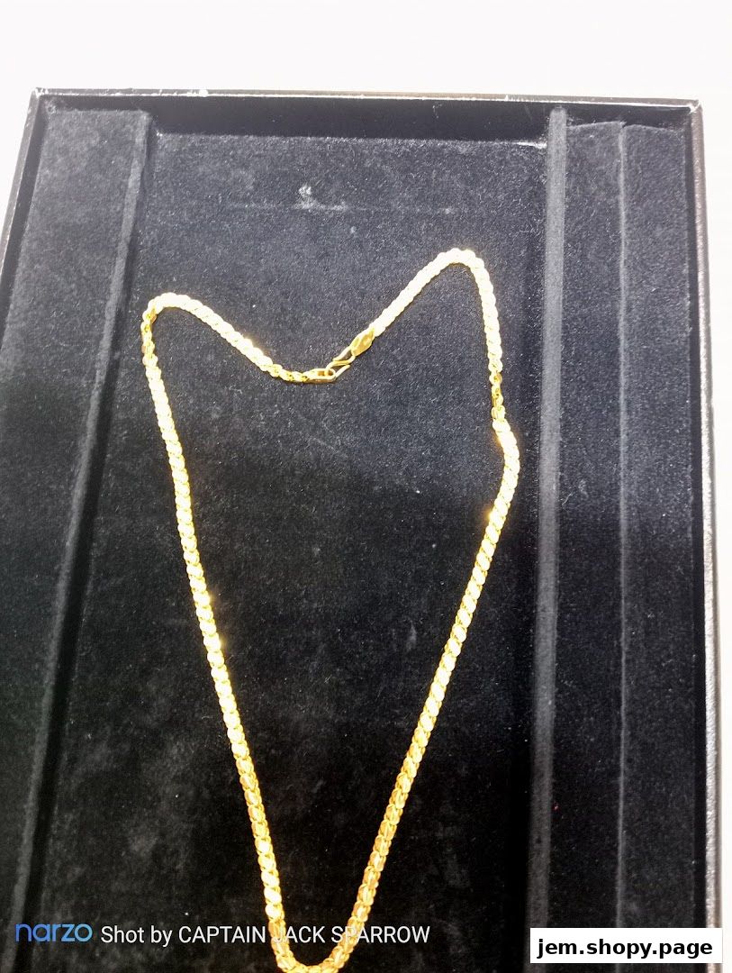 A gold chain displayed on a black velvet tray inside a jewelry box.