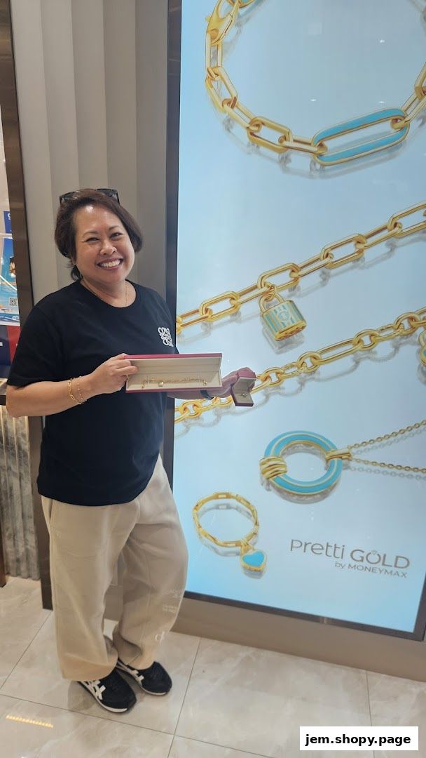 A woman smiles holding a jewelry box in front of a display of gold jewelry.