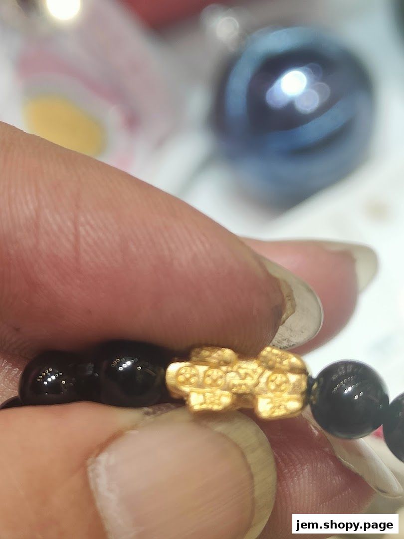 Close-up of a hand holding a black beaded bracelet with a gold charm.