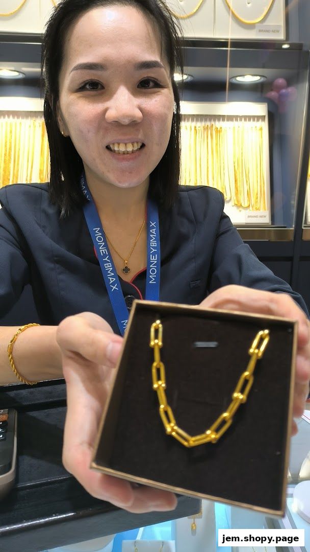A smiling woman presents a gold chain necklace in a display box at MoneyMax Pawnshop.