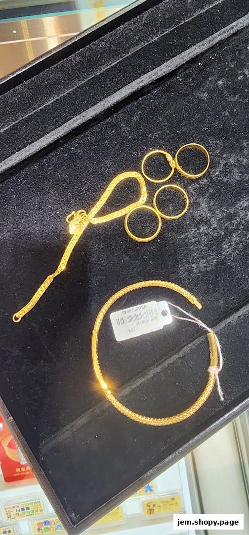 A display of gold jewelry including rings and a bracelet on a black velvet tray.