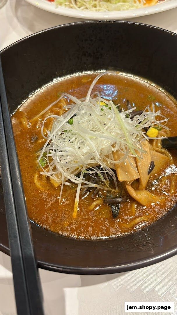 A close-up of a steaming bowl of ramen with broth, noodles, and toppings.