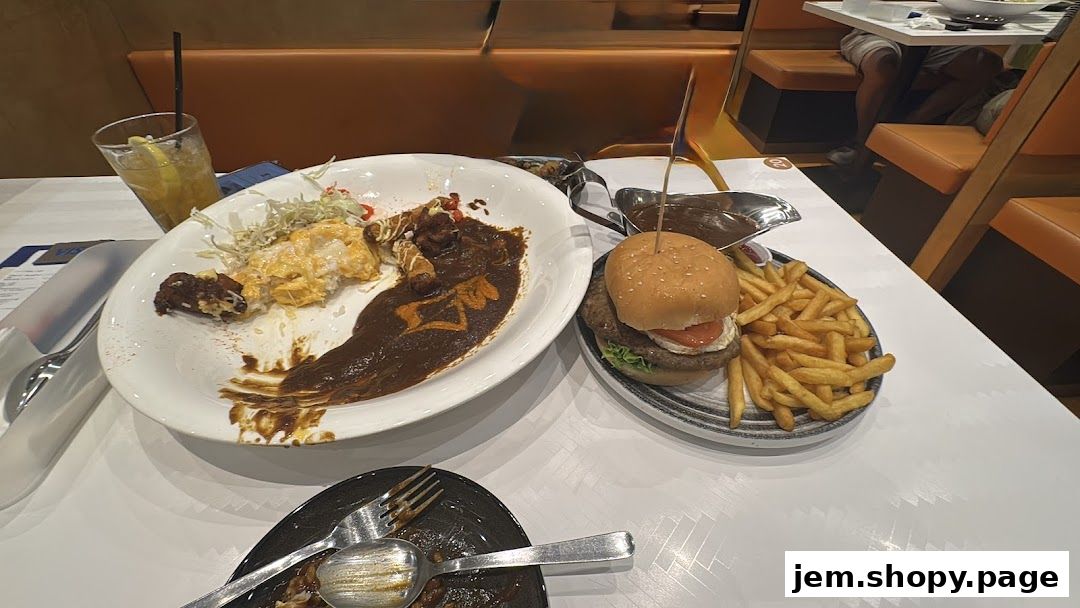 A table with partially eaten food, including curry, a burger, fries, and a drink.