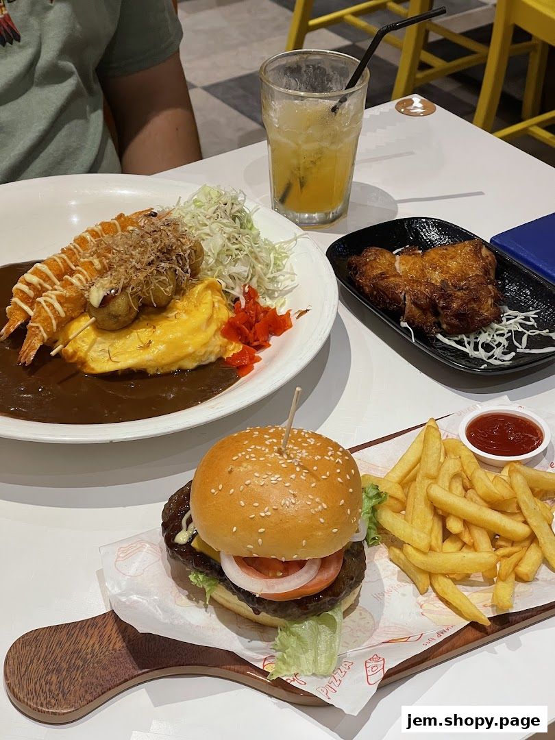 A table laden with delicious food including a burger, fries, curry, and a refreshing drink.