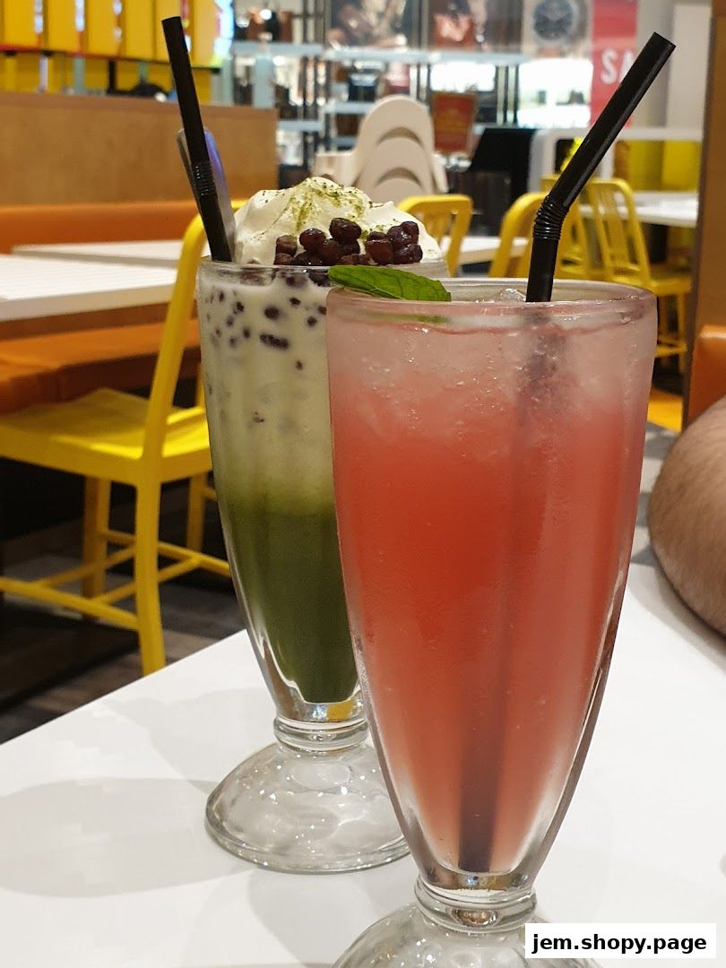 Two refreshing drinks, one green with red beans and whipped cream, the other pink.